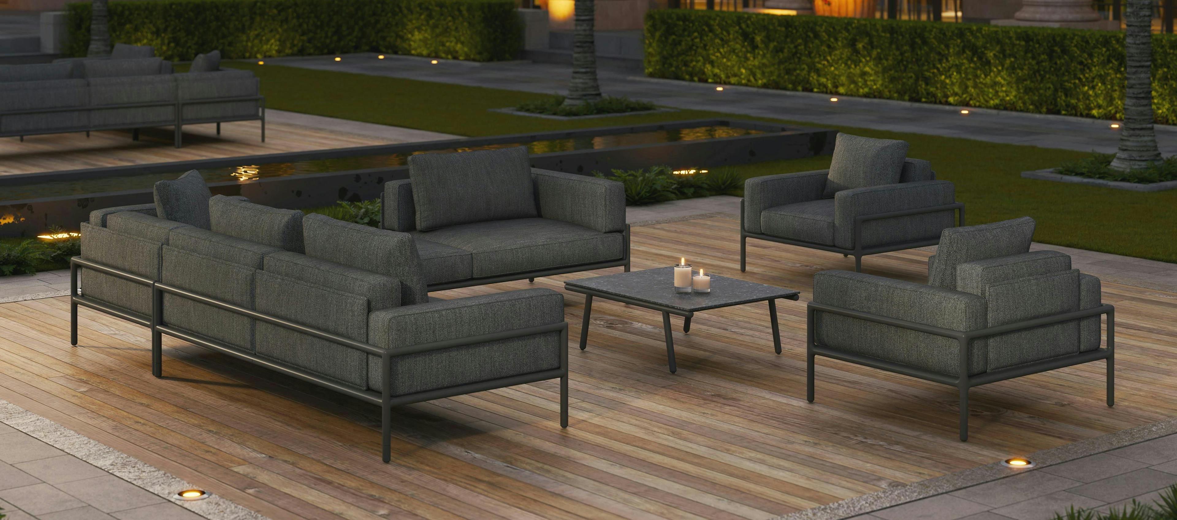 Moto collection by Ann Marie Vering, image shows seating set with modular sofas, lounge chairs, and a coffee table in the center on a wooden deck in nighttime setting.