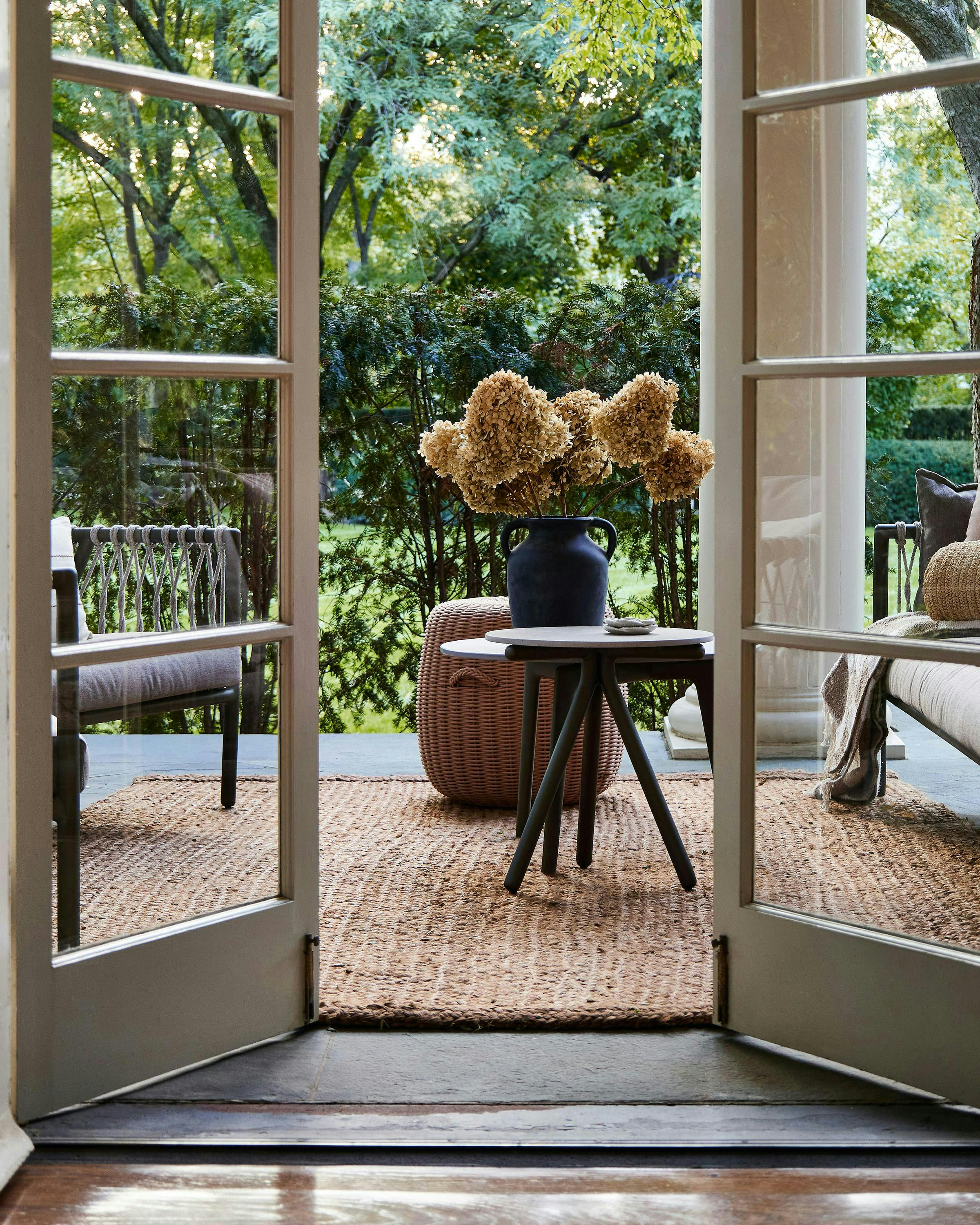 Kate Marker Trade Program Open door windows from inside home reveal garden with seating set.